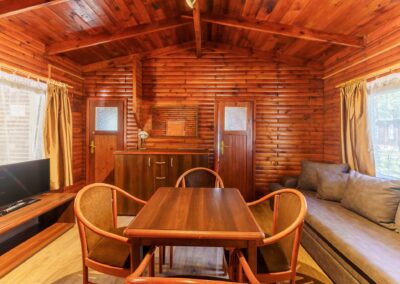 Salon z jadalnią w domku drewnianym — widok na sypialnie
