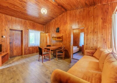Wnętrze domku drewnianego — salon z sofą i stołem jadalnym